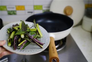 轻奢不粘锅里加少许油，将摘切好的红苔菜下锅炒至挂味。