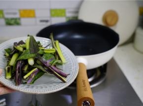 轻奢不粘锅里加少许油，将摘切好的红苔菜下锅炒至挂味。