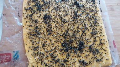 整平整后，把保鲜袋剪开，刷上蛋液，撒上黑芝麻