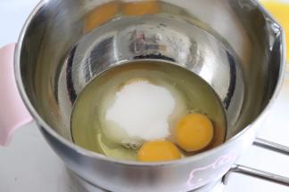 全蛋加入细砂糖，放置到50度左右的温水中，让蛋温稍微升高，并用电动打蛋器打发。