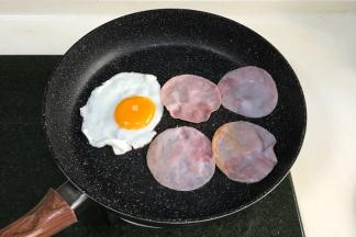 在不粘锅内加入鸡蛋和火腿片，用中小火煎制下。