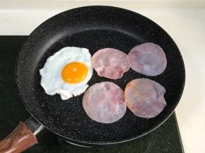 在不粘锅内加入鸡蛋和火腿片，用中小火煎制下。