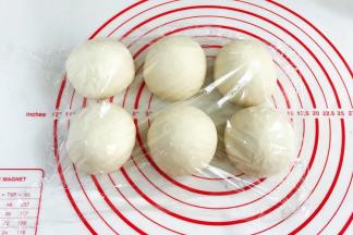 将发酵好的面团取出排气，平均分成6份，接着滚圆，盖好保鲜膜松弛15分钟。