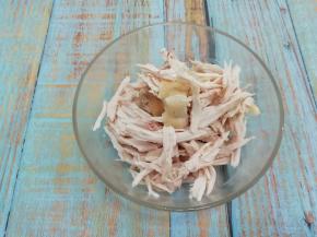 煮好的鸡捞出来，放入冰水中冰五分钟，然后把鸡肉顺着纹路撕成条，放入碗中