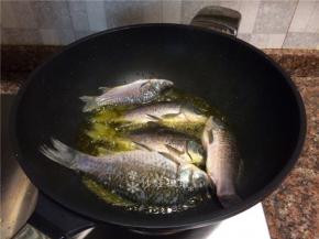 放入鲫鱼炸至表皮焦黄。