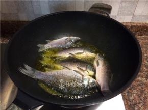 放入鲫鱼炸至表皮焦黄。