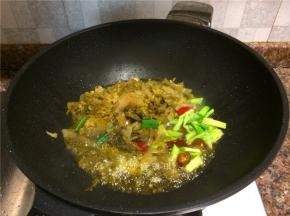 放入酸菜、蒜苗头、泡姜和泡椒翻炒2分钟。