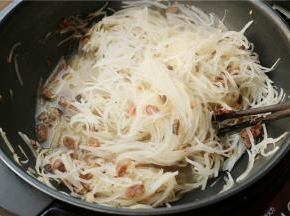 加入盐、白糖和120克水，煮一会至萝卜丝变软。