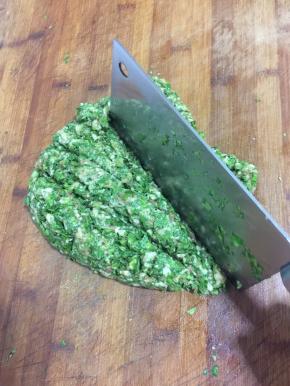 五花肉糜加入清洗干净的芹菜叶，放入一勺盐用刀剁成细细的肉馅儿。