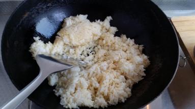 锅里放油下一半葱白和抓匀的米饭煸炒。