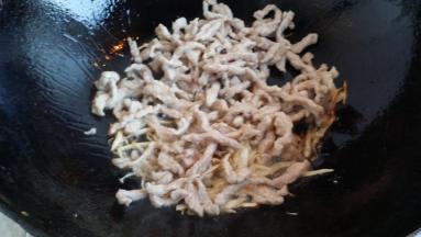 锅里放少许油放葱姜一起煸炒，淋料酒、放肉丝。