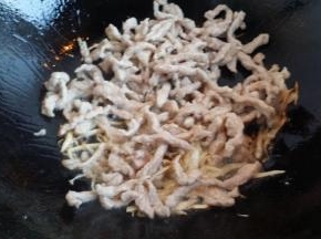 锅里放少许油放葱姜一起煸炒，淋料酒、放肉丝。