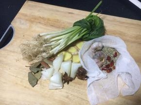 浸泡牛肉时准备佐料：小香葱打结、姜切片、洋葱切块，草果用到拍瘪，八角掰碎，香叶清洗干净、干辣椒和小茴香、蒜包在料包里。