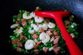 看见蒜薹断生变色的时候，加入切丁的火腿肠继续大火翻炒片刻。