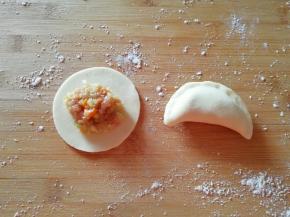 取一个饺子皮，放上萝卜大肉馅，将边缘捏紧。