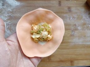 将剂子擀成圆形的薄片，舀一勺馅放在中间白色的部分。