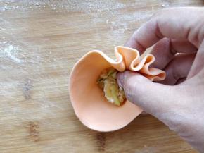 用大拇指尖端压住馅，和食指中指一起边捏褶边逆时针转动，将烧麦包好。