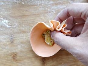 用大拇指尖端压住馅，和食指中指一起边捏褶边逆时针转动，将烧麦包好。