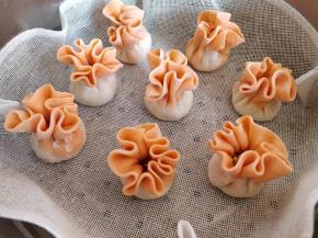 把包好的烧麦垫好屉布，摆入蒸锅中。