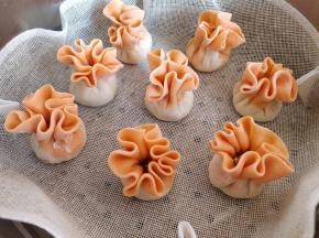 把包好的烧麦垫好屉布，摆入蒸锅中。