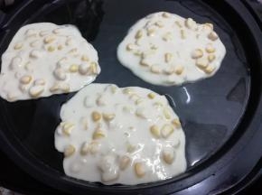电饼铛中加入适量的油预热，然后用勺子舀一勺玉米面糊倒入锅中摊平