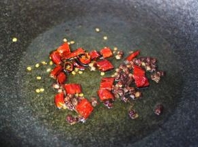 锅烧热后倒入花生油烧至六成热时，先爆香花椒和干辣椒。