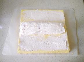 14把剩下的奶油涂满橘子的缝隙，提起两端油纸向中间卷，卷成O形包上油纸，放冰箱冷藏一小时定型。