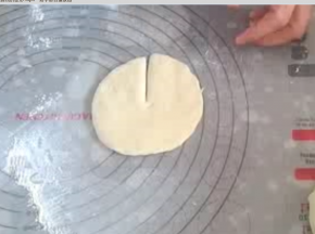 取其中一份，压扁，排气，擀成圆片。直径大约拇指与食指张开的距离。沿圆形片半径切开。