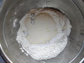 在中间挖个坑，将蜂蜜和140克淡奶油倒入其中，用硅胶刮刀拌匀。