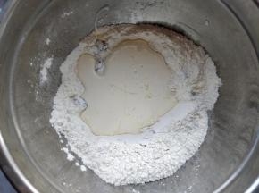 在中间挖个坑，将蜂蜜和140克淡奶油倒入其中，用硅胶刮刀拌匀。