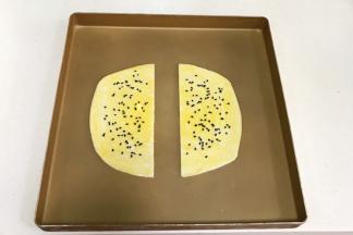 给飞饼刷上蛋黄液，撒上少许黑芝麻。