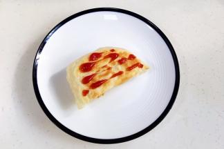 取一块烤好的飞饼，挤上番茄酱。