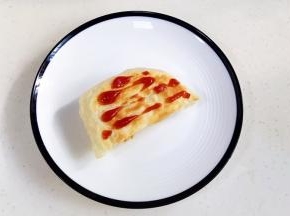 取一块烤好的飞饼，挤上番茄酱。