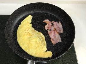 把剩下的蛋黄液和蛋白一起搅打均匀，然后放入煎锅中煎熟，把培根也入锅煎一煎。
