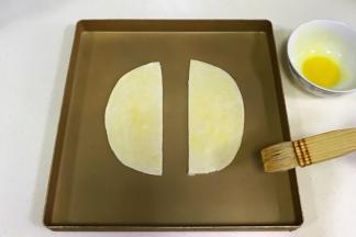 把飞饼一切为二，放入不粘烤盘中。