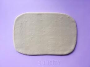 揉面垫上撒适量的干粉，将揉好的面团擀成小号保鲜膜大小的长方形 ，包裹上油纸，装入保鲜袋入冰箱冷冻 