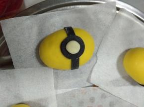 在椭圆形的面团中间贴上黑色长条，黑色圆形，白色圆形，依次贴好