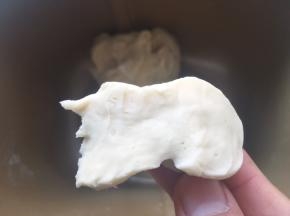 加牛奶启动揉面程序将材料揉成面团，揉好的面团切开，横切面面团紧实，孔洞很少
