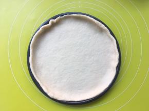 将擀好的面片盖在披萨盘上，预热烤箱190度
