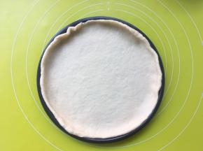 将擀好的面片盖在披萨盘上，预热烤箱190度

