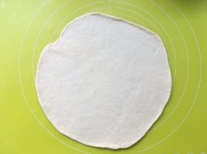 将面团擀成比8寸披萨盘大一点的圆片
