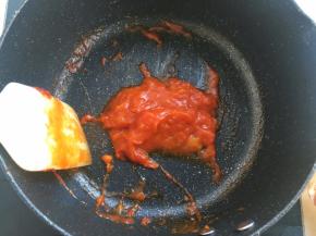 加入番茄酱，一起翻炒至西红柿融化，变成泥状后关火，用刮刀碾压去掉西红柿皮
