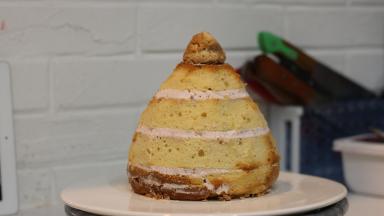 用蛋糕刀修整形状，如果不修整的话成品会显得比较圆胖。取一部分切下的边角料攥紧成团（圆锥形，抹少量奶油固定在顶部）