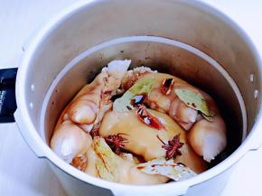 处理好的猪蹄放入高压锅中，加入酱油，讲究，八角，，桂皮，香叶，姜片。