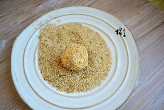 把包好的小圆球放在芝麻中，滚上满满的芝麻，把所有的小圆球都裹满，放在盘中备用