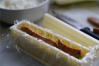 再将煮好的香肠改刀，铺在里面，在最上面再用米饭盖住，压紧实了就可以。