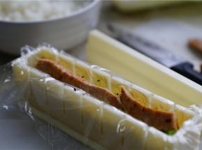 再将煮好的香肠改刀，铺在里面，在最上面再用米饭盖住，压紧实了就可以。