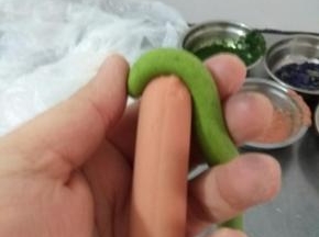 面条横着压住火腿肠一头，然后卷起