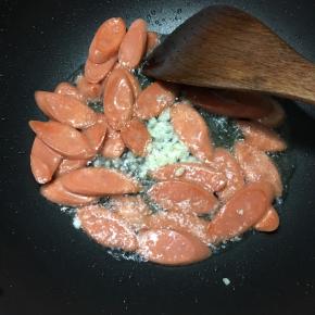 火腿肠表面微焦时下入蒜末煸出香味。