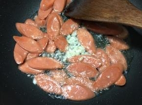 火腿肠表面微焦时下入蒜末煸出香味。